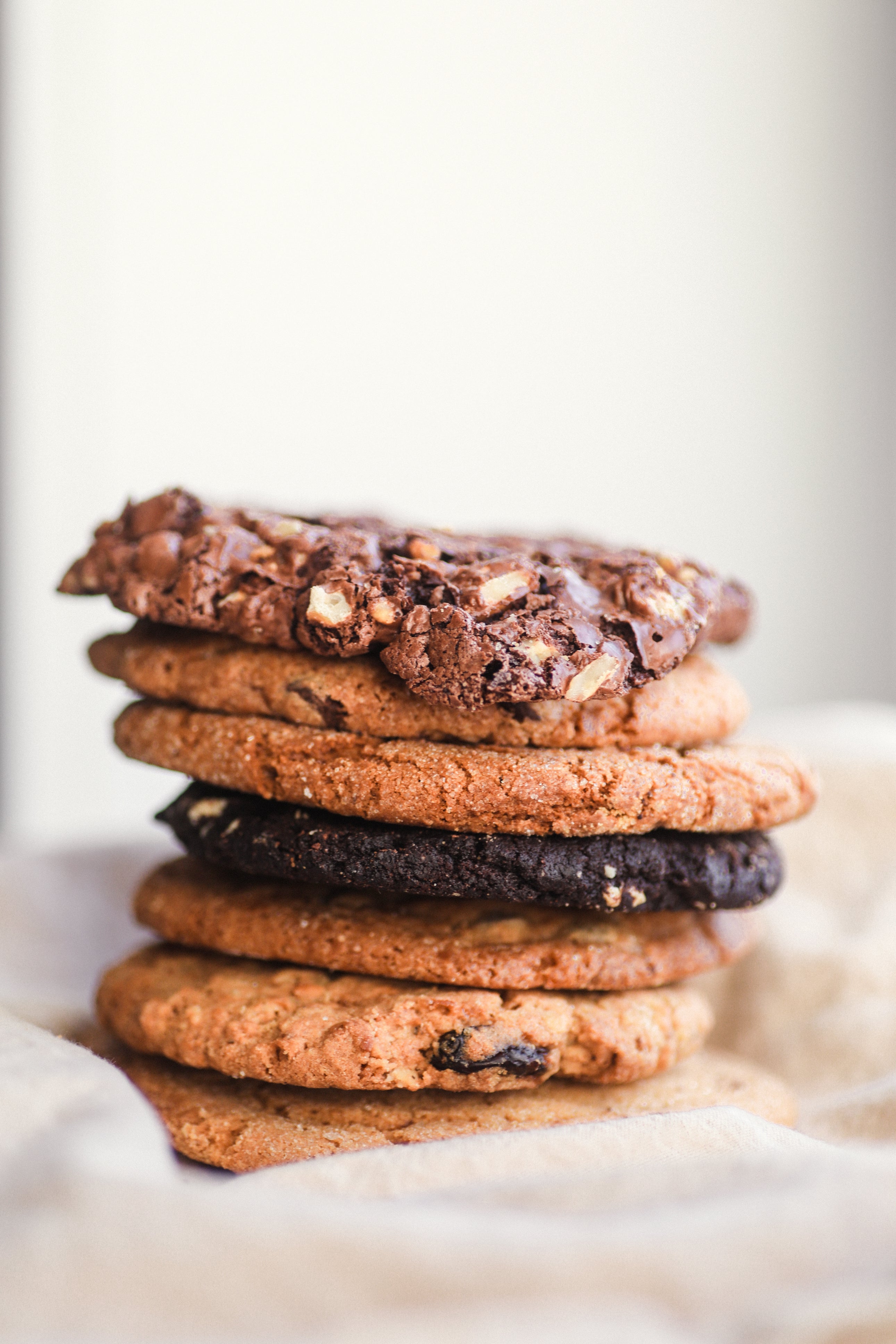 An image of stacked cookies as offered by Juniper Cafe, including spicy ginger, chocolate chips, oatmeal and more.