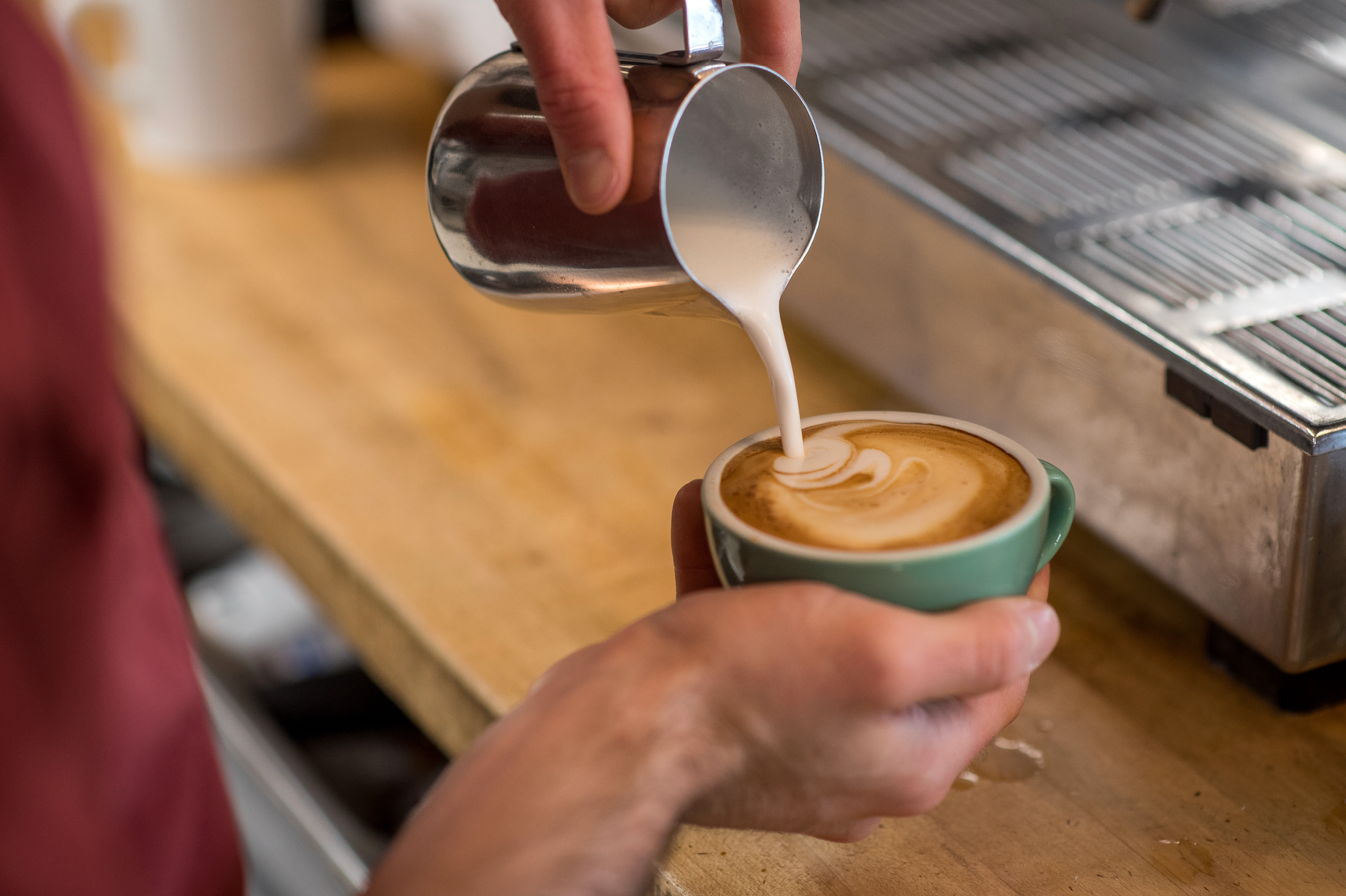 A picture showing the addition of cream milk into a cup of coffee with gentleness and care at Kingston's Juniper Cafe.