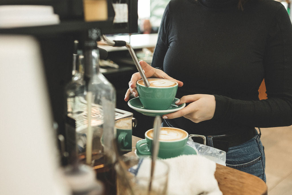 A picture of staff at Kingston's Juniper Cafe serving coffee with a heart shaped cover.