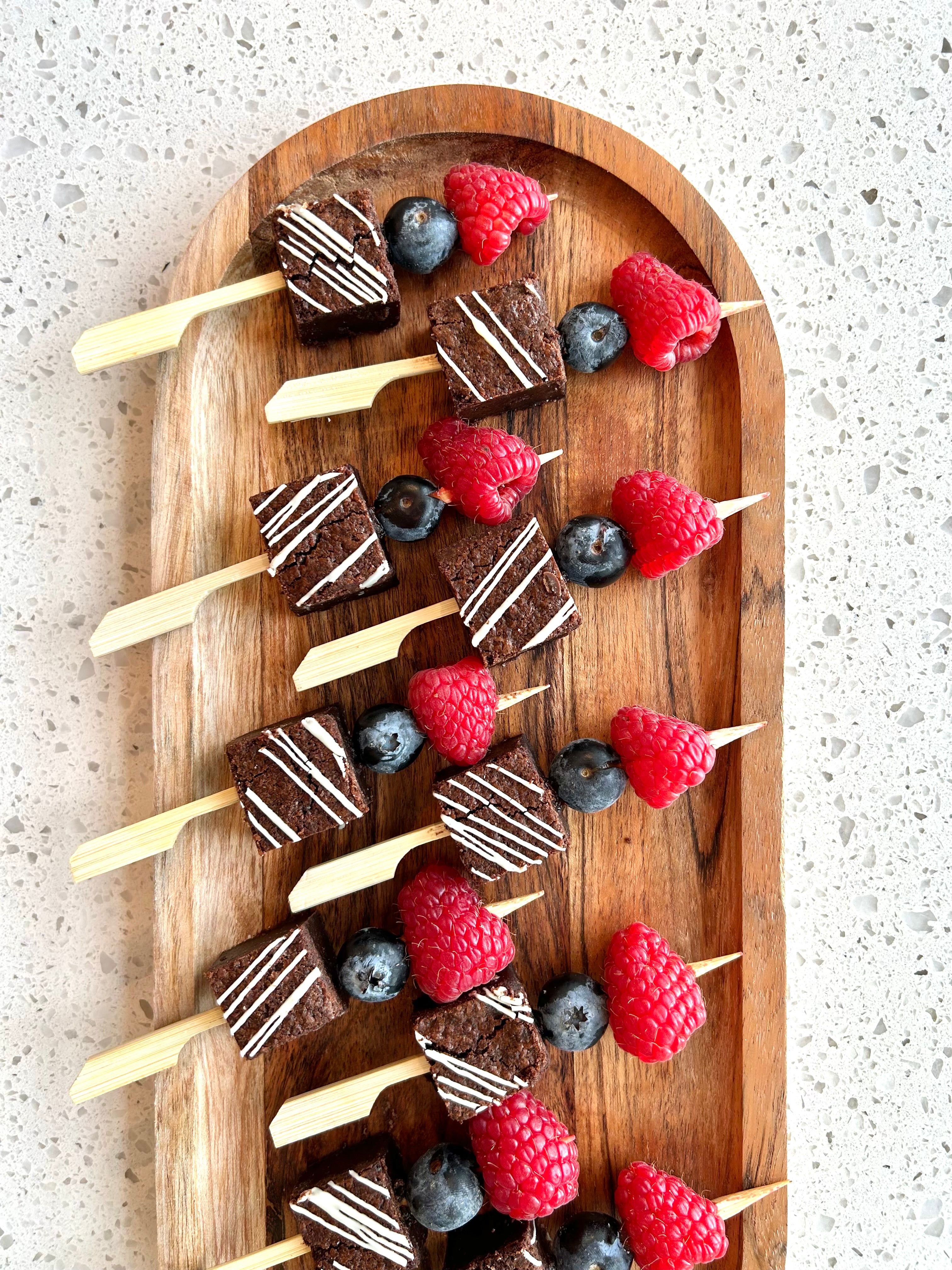 A picture showing a platter of dessert brownies, raspberries and blueberries.