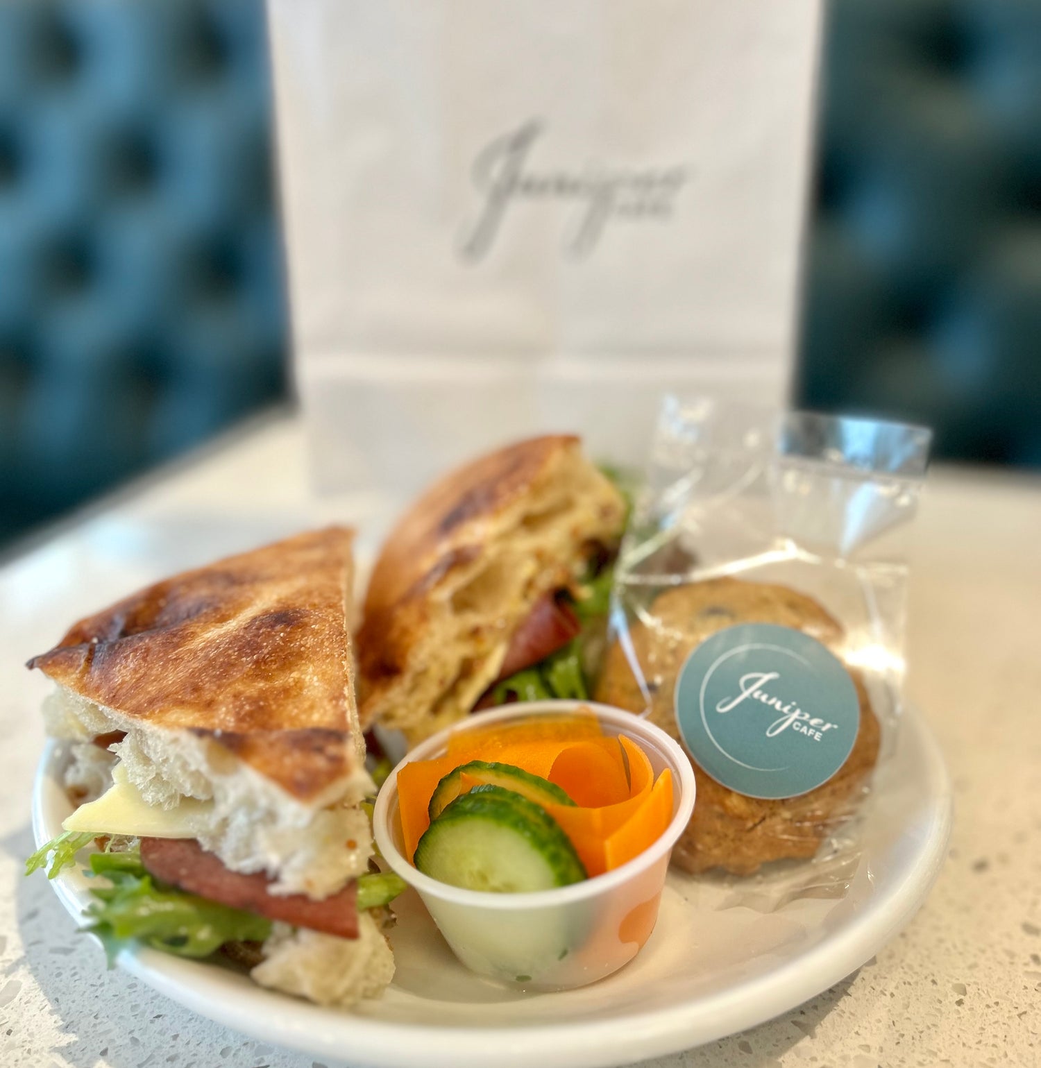 An image showing a dish catered by Juniper Cafe, that includes a triangular sandwich, vegetables, and a cookie.
