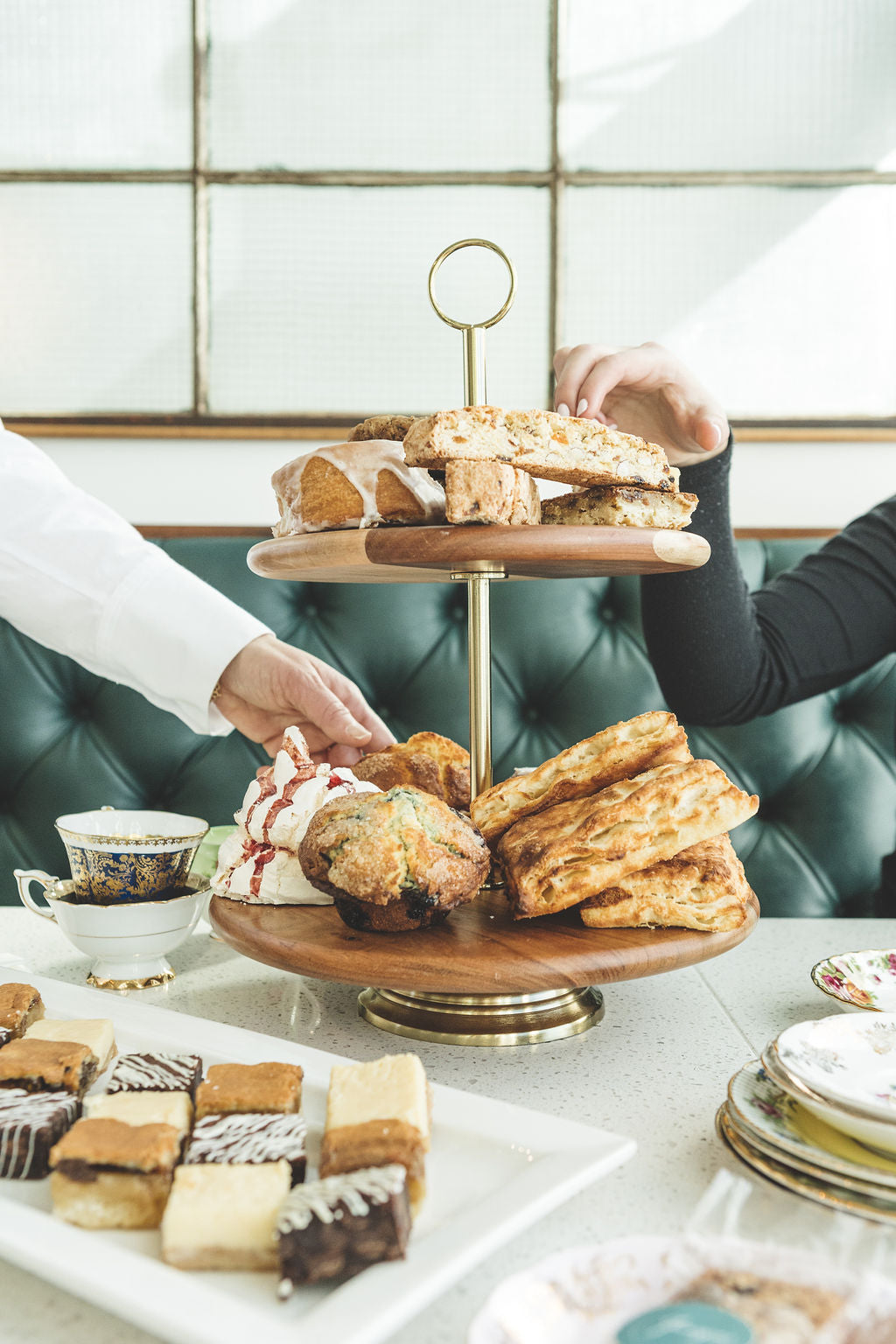 A picture showing people reaching over to grab desserts from an open table serving at Juniper cafe.
